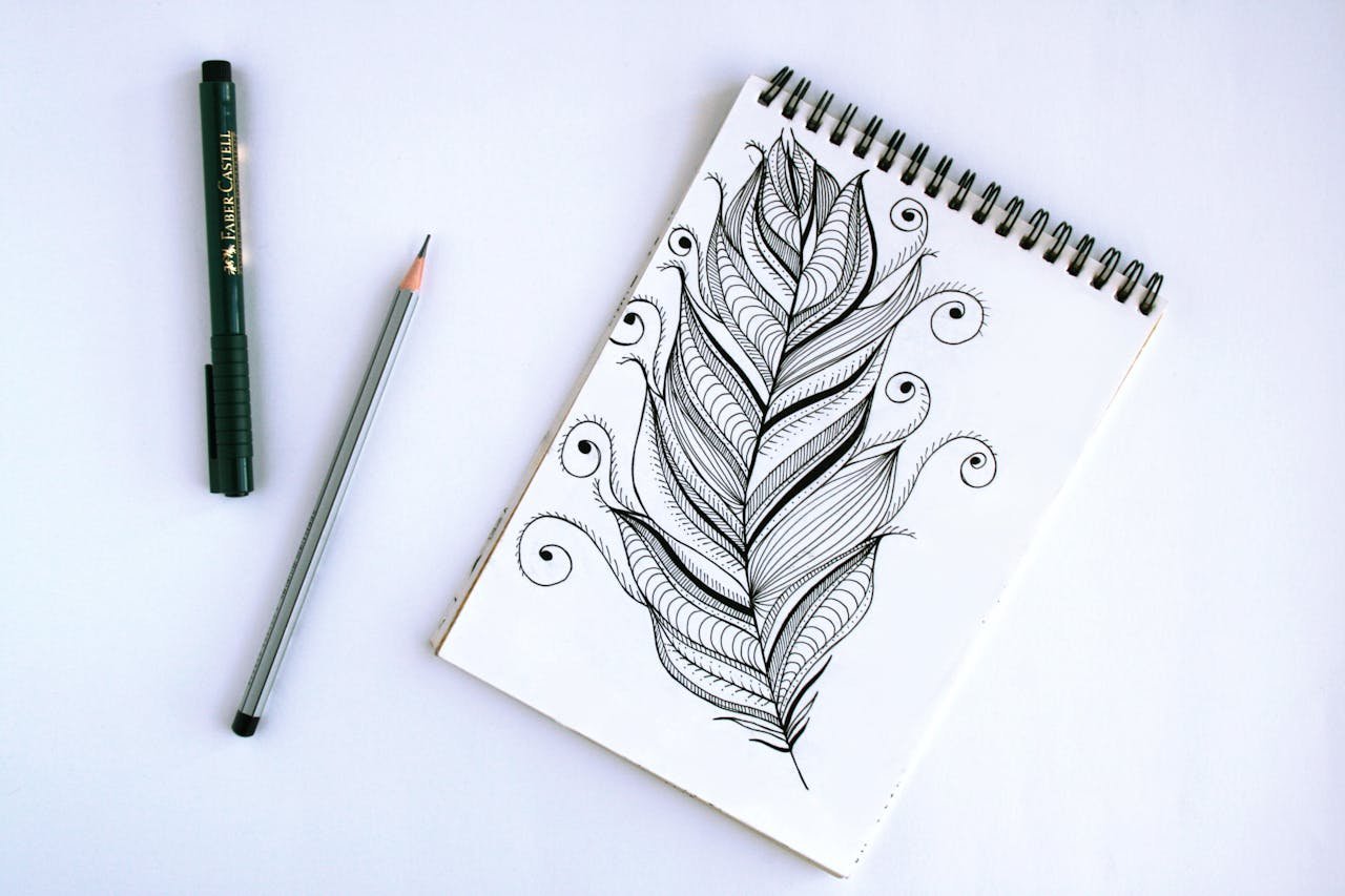 Artistic feather sketch with pen and pencil on sketchpad, showcasing intricate details.